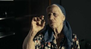אישה זקנה עם מטפחת ראש מביטה בטבעת הנישואין שלה