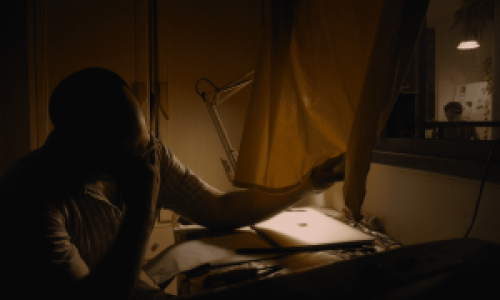 השחקן הראשי יושב בחדר המבודד שלו עם תאורה של מנורת לילה ועוסק באומנות