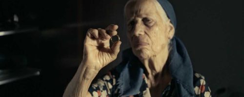 אישה זקנה עם מטפחת ראש מביטה בטבעת הנישואין שלה